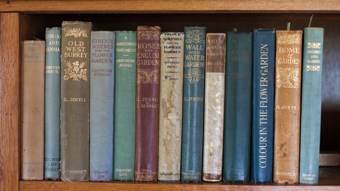 Books on a shelf in the book room at Munstead Wood. The books are written by Gertrude Jekyll and include Old West Surrey, Roses for English Gardens and Colour in the Flower Garden
